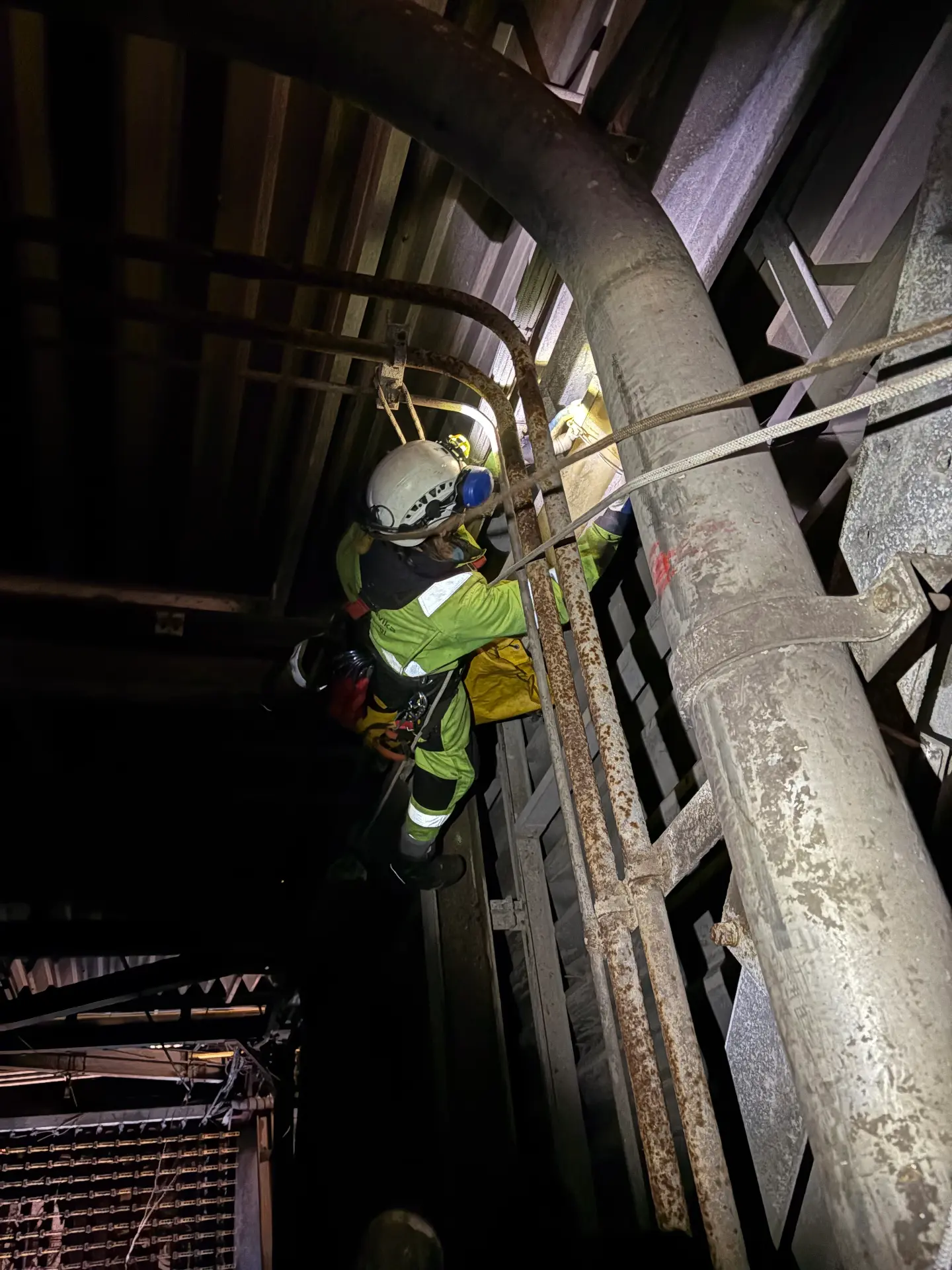 Rope access work inside a dark confined industrial structure.