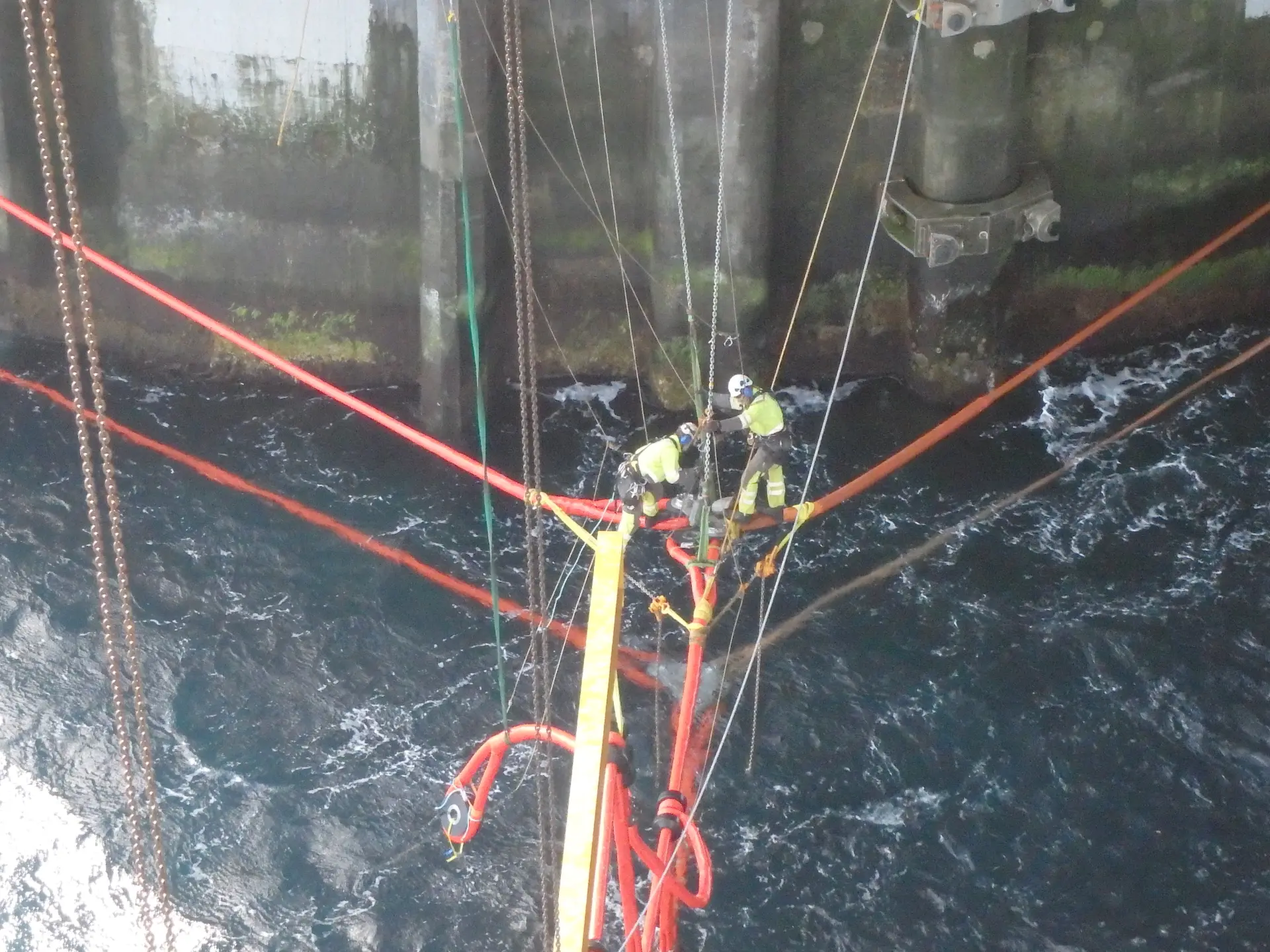 Technicians working at height on rope rigging above water.